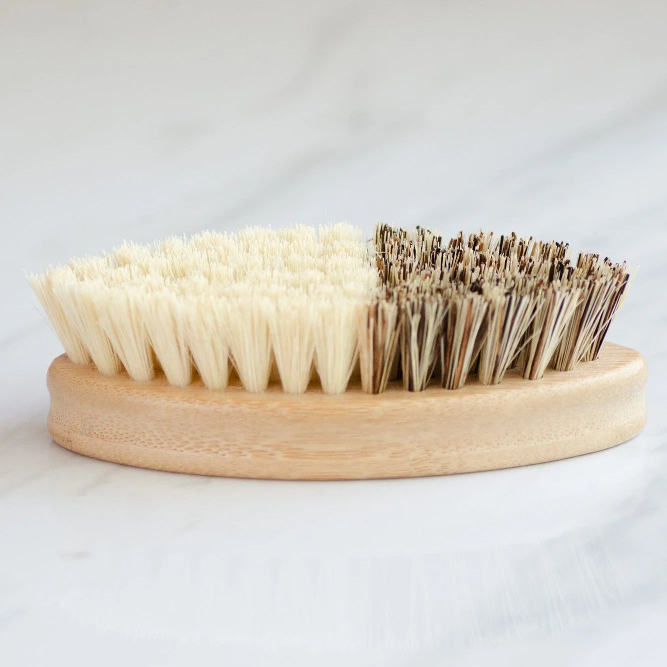 Two-sided brush with natural bristles on a wooden base against a white background